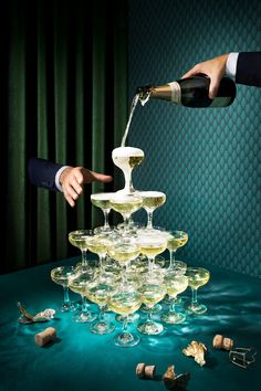 two people pouring champagne into wine glasses on top of a table filled with small objects