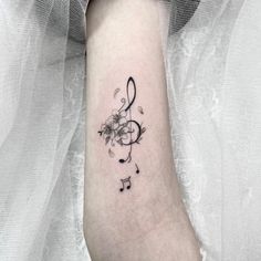 a tattoo with musical notes and flowers on the arm