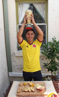 a man in yellow shirt holding up an object over his head with other food on table