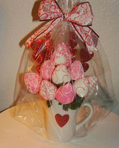 a coffee mug filled with pink and white heart shaped candies in a cellophane bag