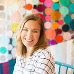 a woman standing in front of a colorful wall