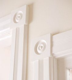 the corner of a room with white trim and moldings on the wall, along with a mirror