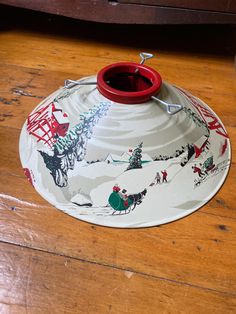 a red cup sitting on top of a wooden table next to a plate with christmas decorations