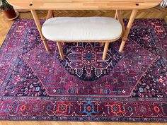 a wooden table with two chairs and a rug on the floor in front of it