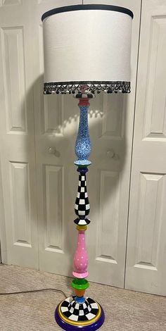 a colorful lamp sitting on top of a table next to a white door with a black and white checkered lampshade