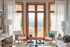 a living room filled with white furniture and lots of windows