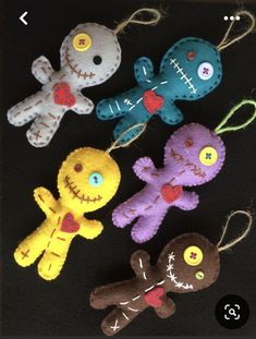 five stuffed animals are hanging from strings on a black surface, one is wearing a red heart and the other has a blue eye