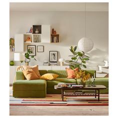 a living room with green couches and pictures on the wall above them, along with a coffee table