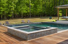 a hot tub sitting on top of a wooden deck next to a pool surrounded by trees