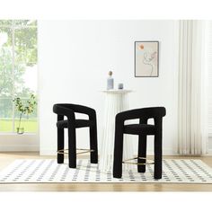 two black chairs sitting next to each other on top of a white and black rug