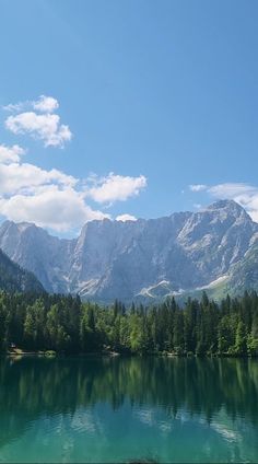 a lake surrounded by mountains and trees under a blue sky