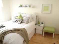 a white bed sitting in a bedroom next to a green chair and window on top of a hard wood floor