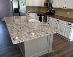 a kitchen with white cabinets and granite counter tops