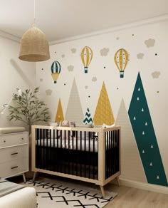 a baby's room with a crib and wallpaper featuring hot air balloons