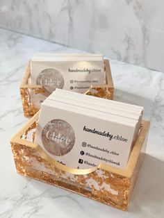 two business cards sitting on top of each other in a wooden box with gold foil