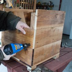 a man is using a drill to attach the top of a piece of wooden furniture