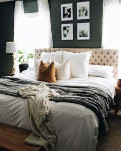 a bed with pillows and blankets on top of it in front of two framed pictures