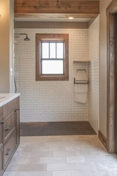 a large bathroom with white tile and wood trim on the walls, along with a window