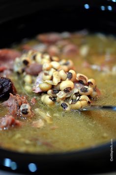 a black bowl filled with soup and meat