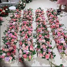 several rows of pink and white flowers on the floor in front of two women standing behind them