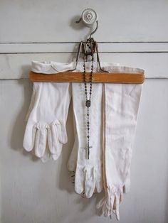 an old pair of white gloves hanging from a hook on a door with beads and chains attached to it