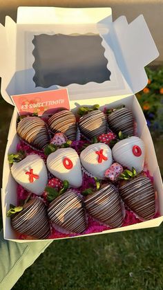 a box filled with chocolate covered strawberries on top of a green grass covered field