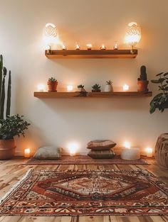 candles are lit on the wall above a rug in a room with potted plants