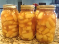 three jars filled with pickles sitting on top of a counter