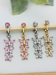 four pairs of earrings with pink and white butterflies hanging from the end of each ear