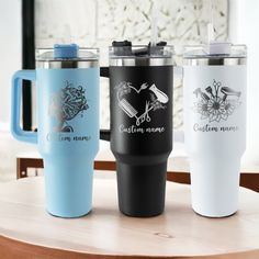 three travel mugs sitting next to each other on a table