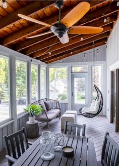 a porch with chairs, table and ceiling fan