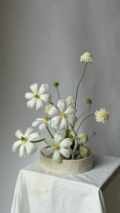 white flowers are in a vase on a table