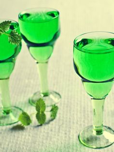 three glasses with green liquid are sitting on a table