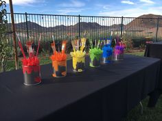 there are many different colored cups on the table with straws in them and one is empty