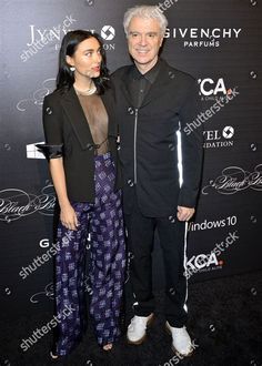 two people posing for the camera at an event, one is wearing black and the other is