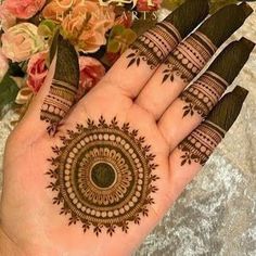 a woman's hand with henna tattoos on it and flowers in the background