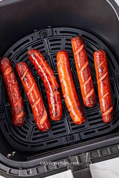 four hot dogs are being grilled on a griddle in an air fryer