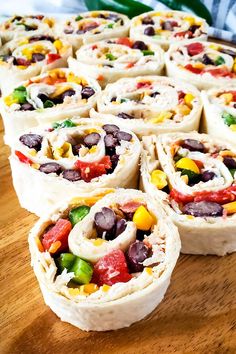 several burritos are stacked on top of each other with peppers and black beans