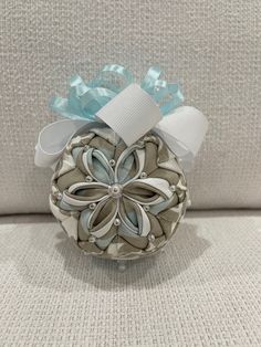 an ornament made out of fabric and ribbon on a white couch with blue bows