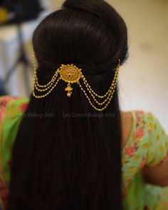 the back of a woman's head wearing a gold hair piece with beads on it