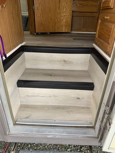 the inside of an rv with wood flooring and black trim on the side door