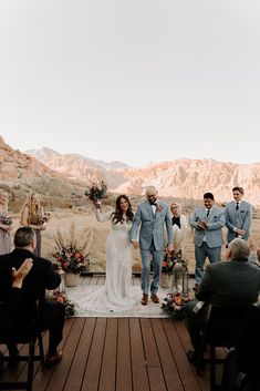 a bride and groom walking down the aisle at their outdoor wedding ceremony with mountains in the background