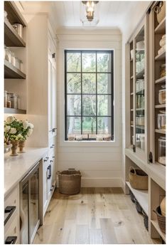 a kitchen with wooden floors and white walls, windows above the sink are open to let natural light into the room