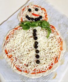 a homemade pizza with cheese and olives on it is decorated like a snowman