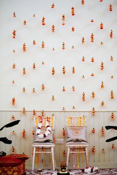 two chairs sitting next to each other in front of a wall with orange and yellow decorations