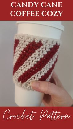 a hand holding a coffee cup covered in red and white crochet