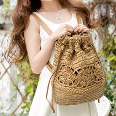 a woman holding a brown crochet bag