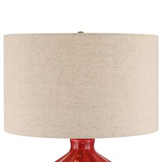 a red table lamp with a beige shade