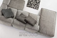 a grey couch with pillows on it next to a black and white wall art piece