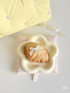 a pastry in a bowl on a pink and white checkered napkin next to a pillow